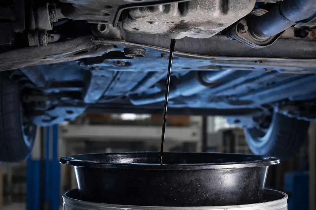 Ölwechsel in einer Autowerkstatt in Seevetal, Motoröl läuft aus dem Fahrzeug in eine Auffangwanne, professionelle Werkstattumgebung.