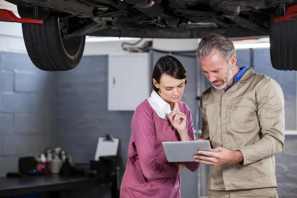 Beratungsgespräch mit Tablet in Autowerkstatt Lüneburg unter Hebebühne
